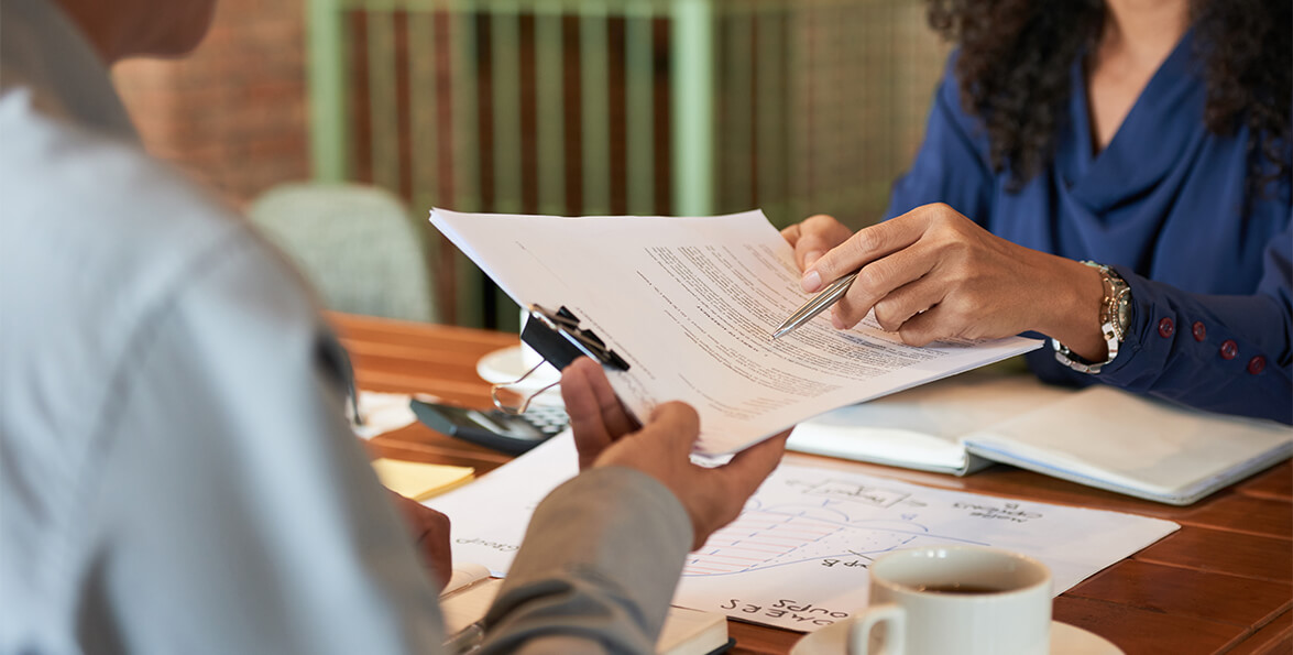Dos personas en una mesa de reunión revisan y señalan un documento impreso