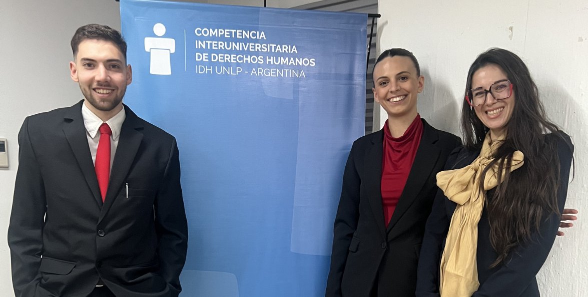 Estudiantes de Derecho de la Universidad Champagnat junto al banner de una competencia interuniversitaria de derechos humanos