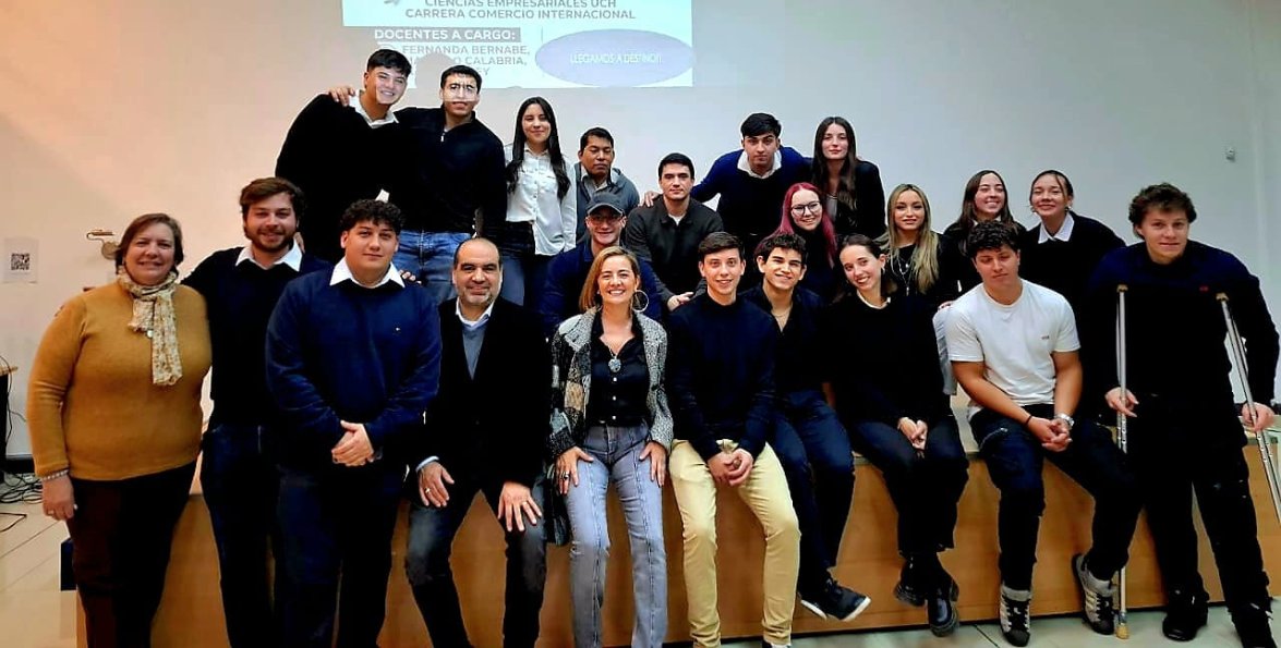 Estudiantes y docentes de cuarto año de Comercio Internacional posan en grupo dentro de un aula.