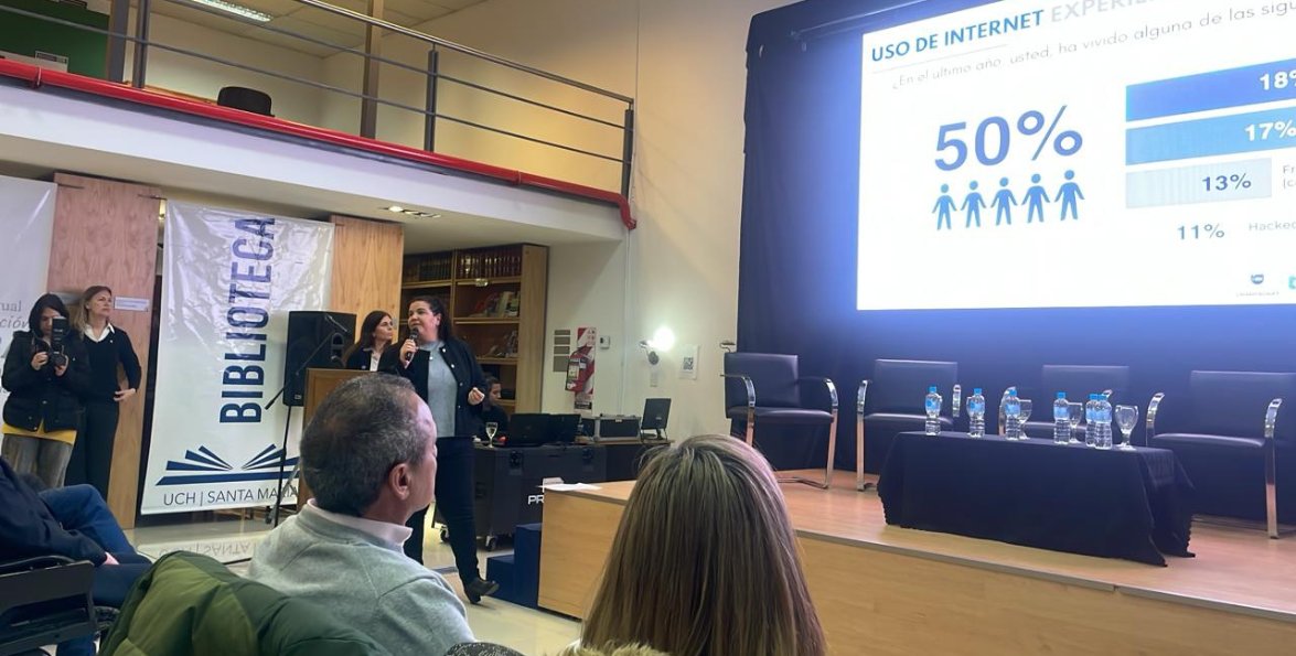 Una investigadora expone ante el público en la biblioteca, con una diapositiva sobre uso de internet proyectada en la pantalla.