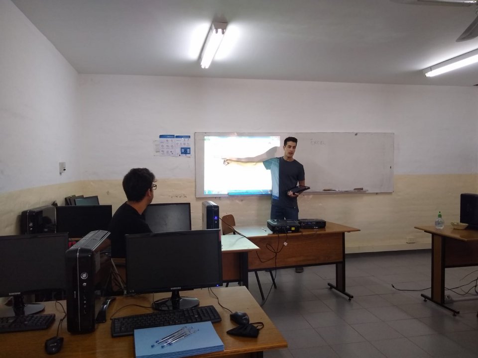 Un estudiante explica finanzas personales con una planilla proyectada en el taller «Abuelos en Red»